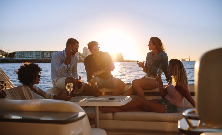 Friends relaxing on a yacht at sunset, enjoying drinks and a scenic boat ride on the water.