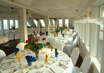 yacht interior showing fancy dinner and lunch tables with Redflower vases on the top 