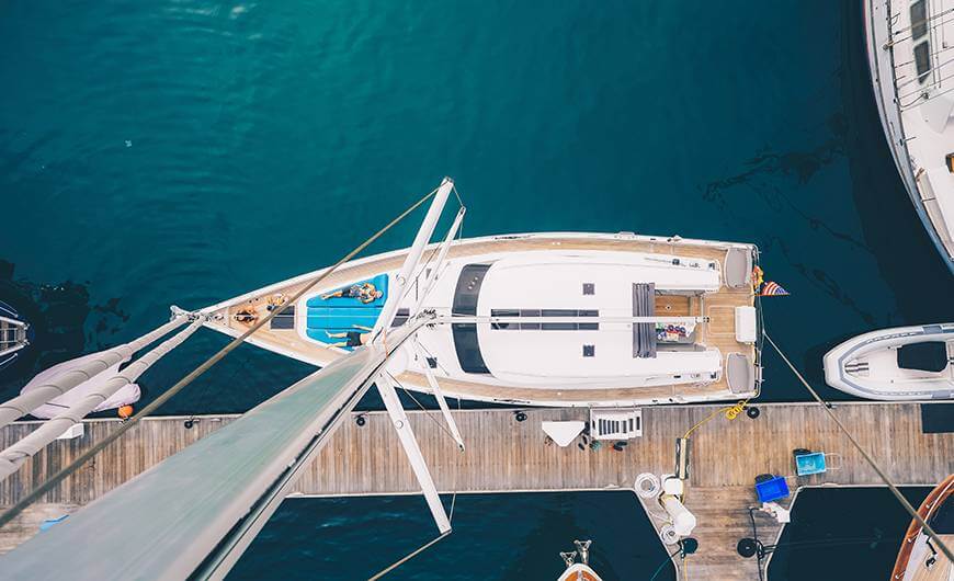 Aerial view of a luxury yacht docked at a marina with clear blue water.